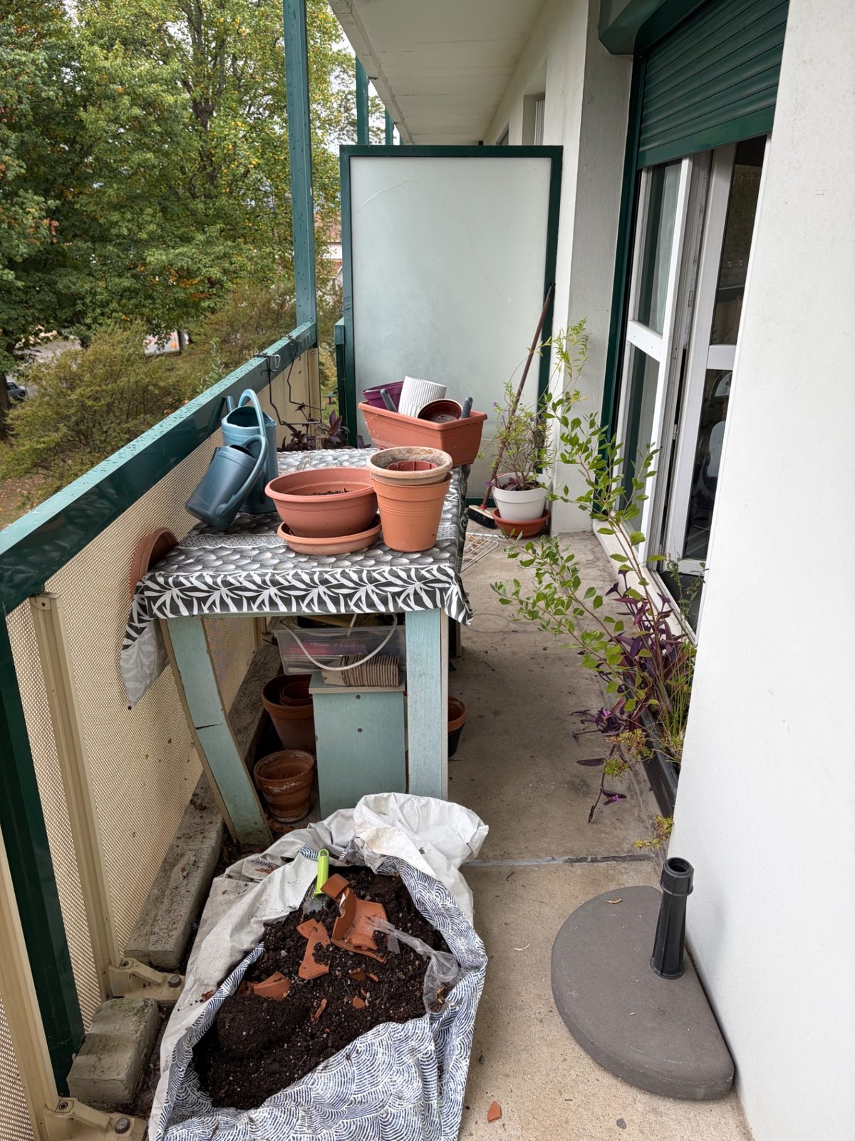 Balcon encombré de pots de fleurs, d'une table et de sacs de terre avant débarras à Béhobie