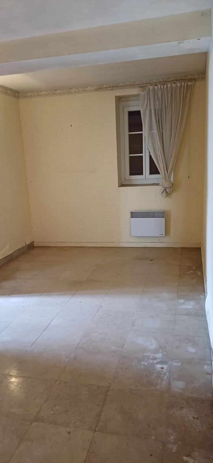 Chambre vide au papier peint ancien avec fenêtre et radiateur, après débarras