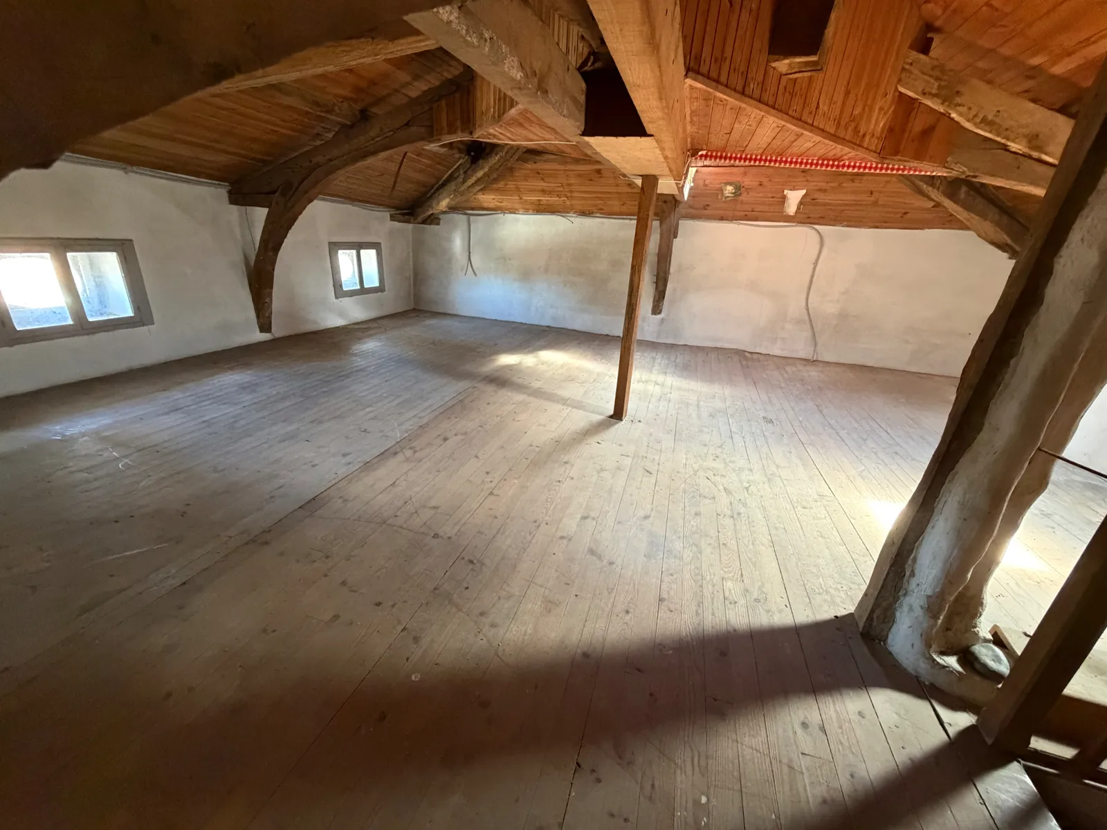 Le même grenier vidé, charpente apparente et plancher en bois, après débarras