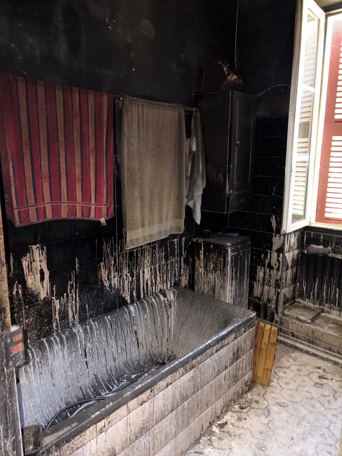 Salle de bain noircie par la suie après un incendie, avant débarras