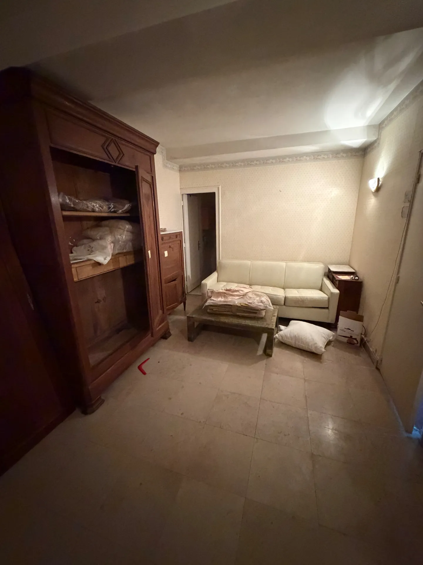 Salon encombré avec grande armoire en bois, canapé et cartons avant débarras