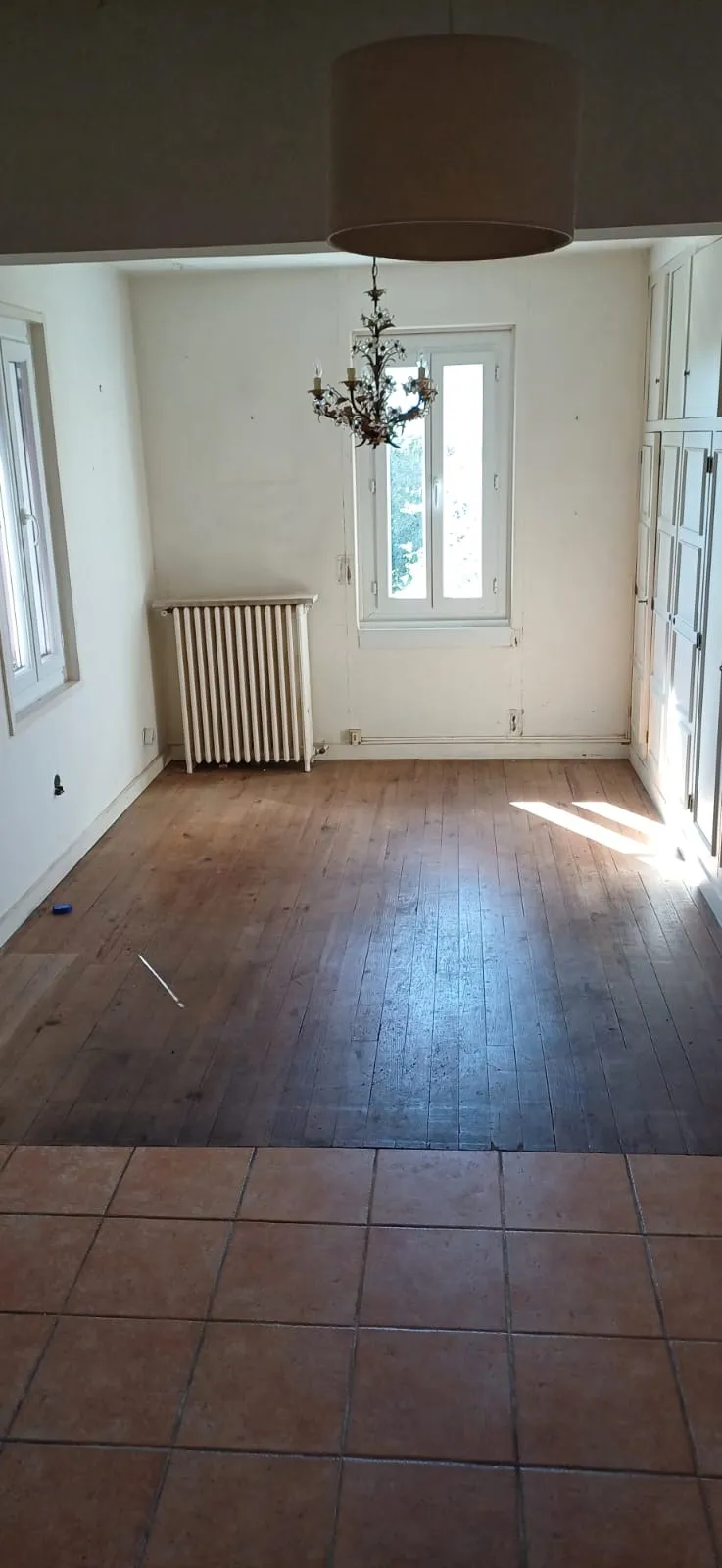Séjour vide avec parquet, lustre et placards, après débarras